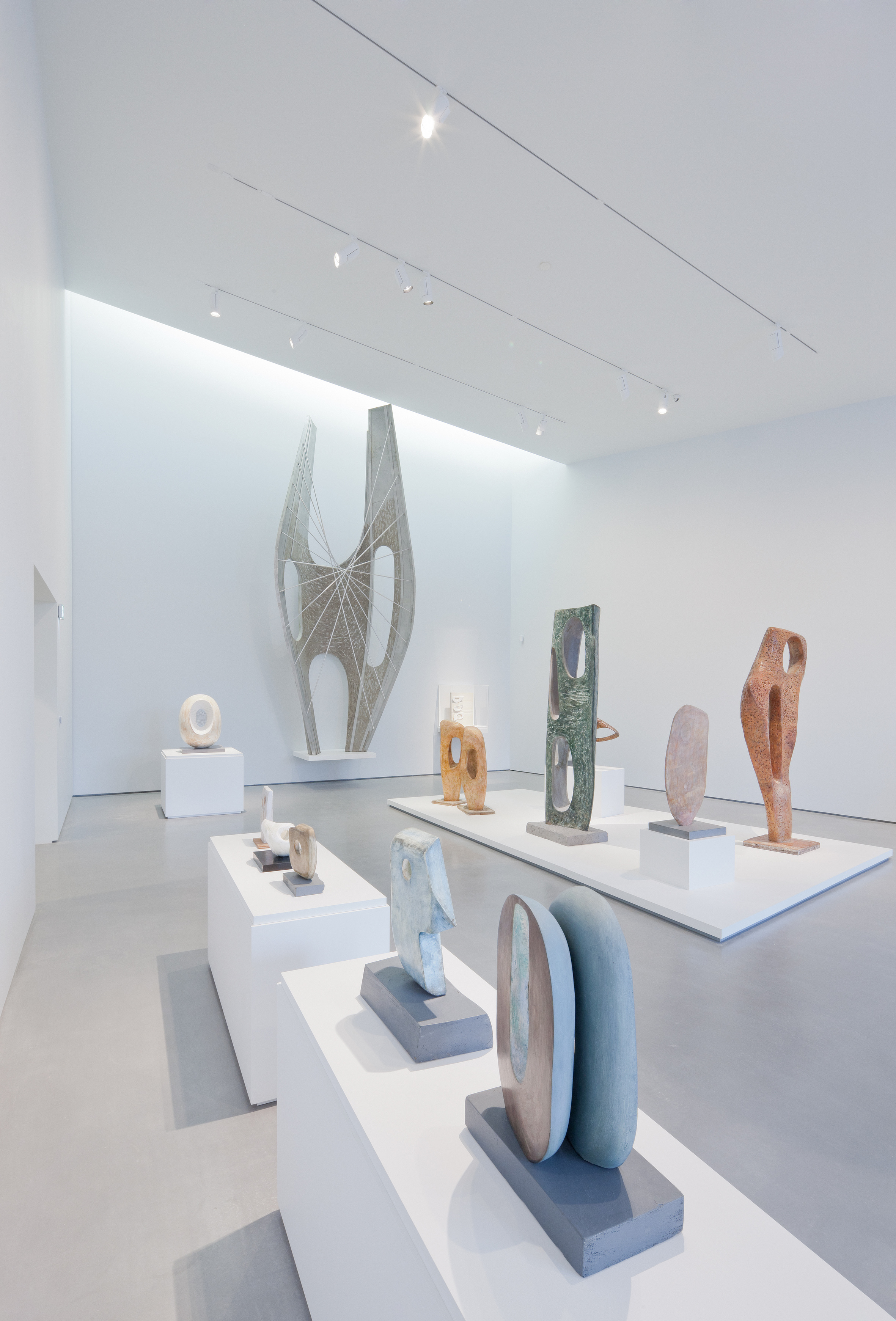 A gallery at The Hepworth, with white walls and grey floor. Hepworth's works are presented throughout the space on plinths.