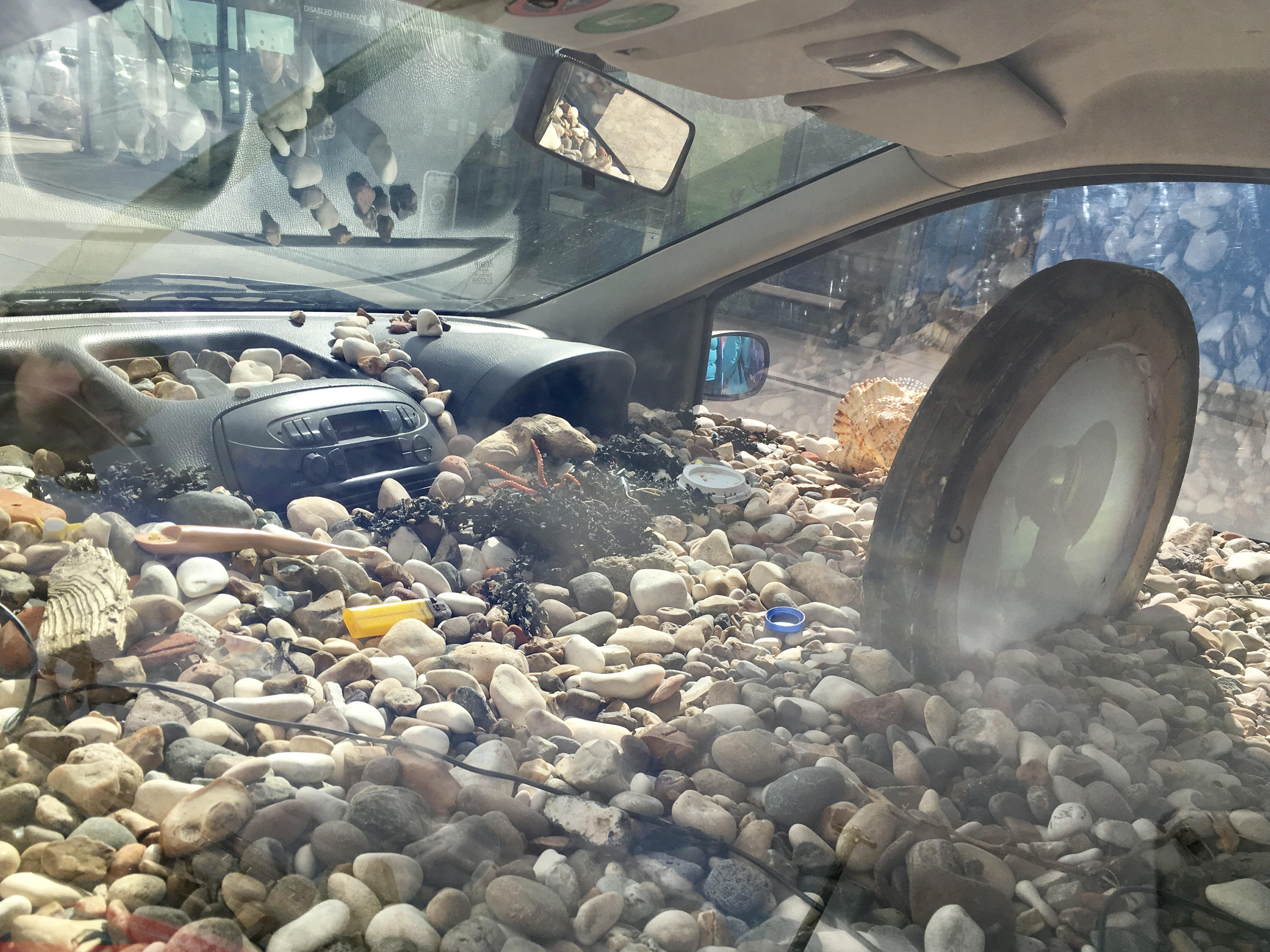 A view of the interior of a car filled with pebbles and shells.