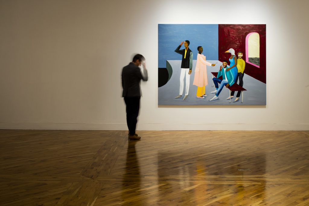 A person stands in a gallery with a colourful painting by Lubaina Himid