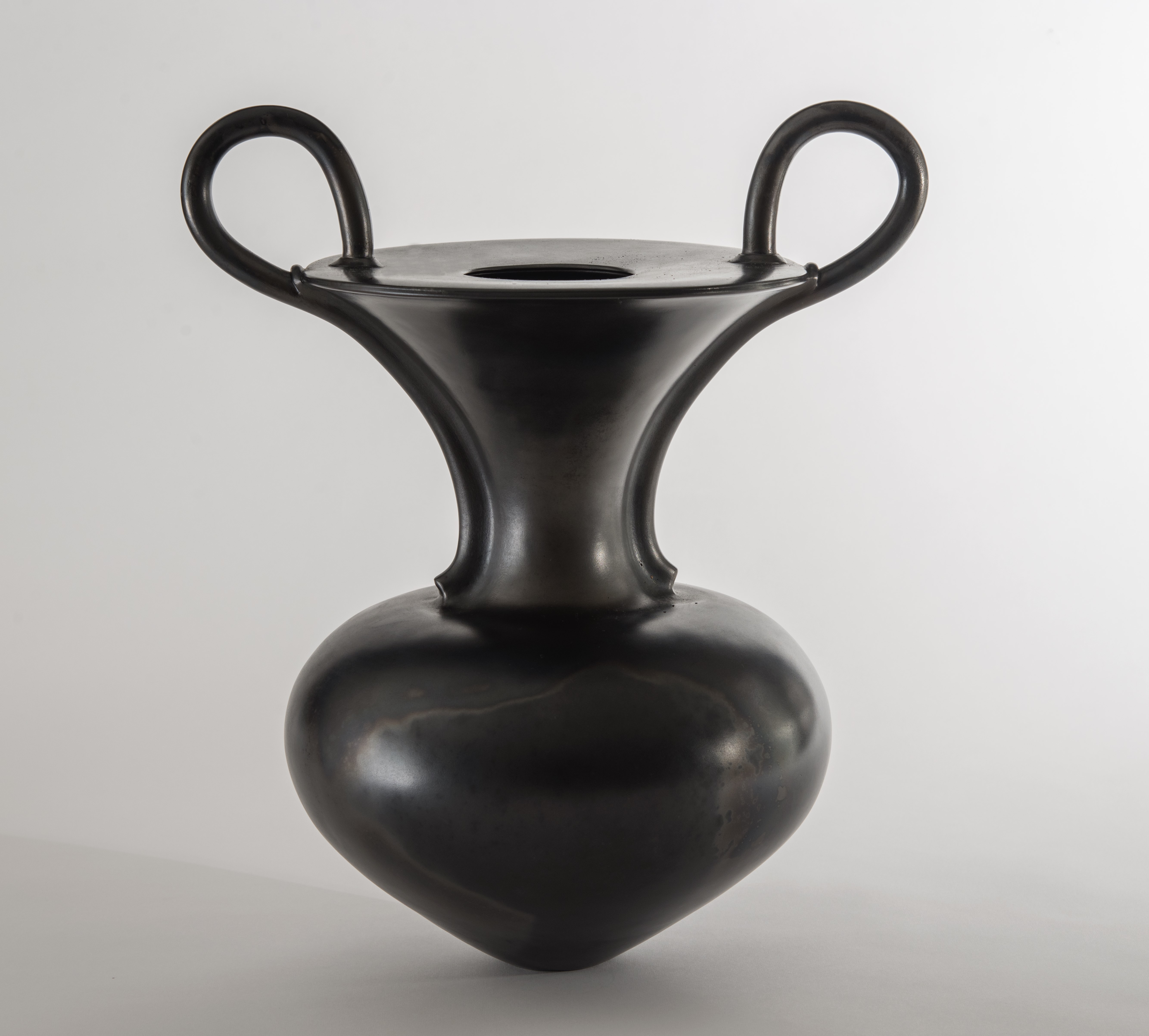 A vase with two handles in a shiny black glaze, on a white background.