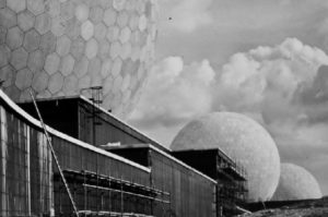 A black and white photograph of the construction of huge white domes that look like golf balls.
