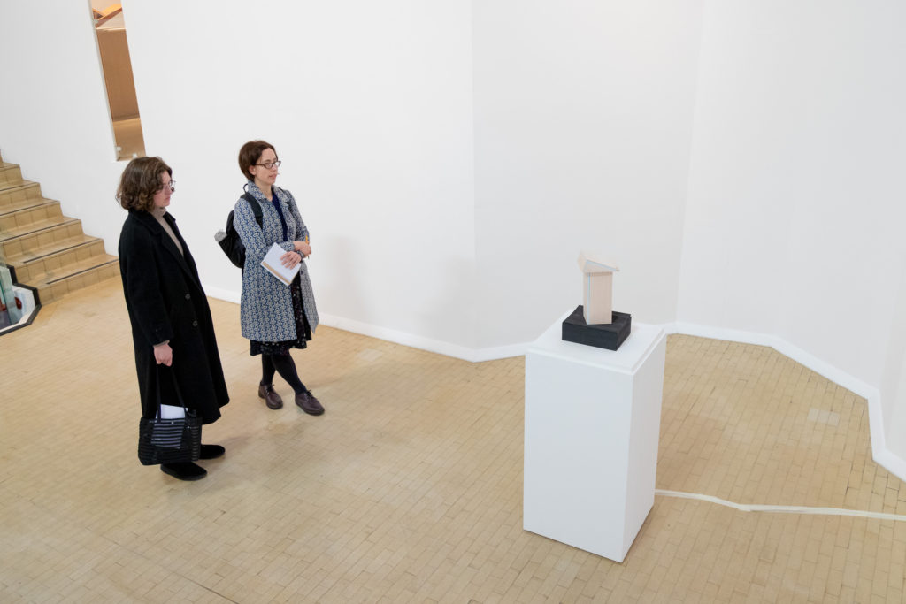 Two people contemplate a sculpture on a white plinth.