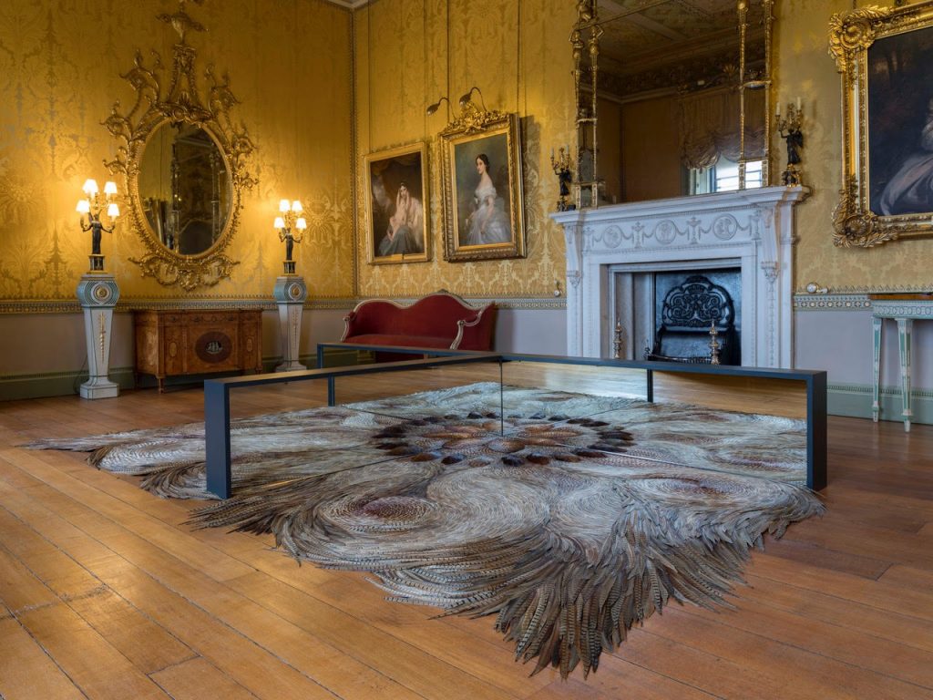 A sculpture made of metal and feathers in the room of a historic house.