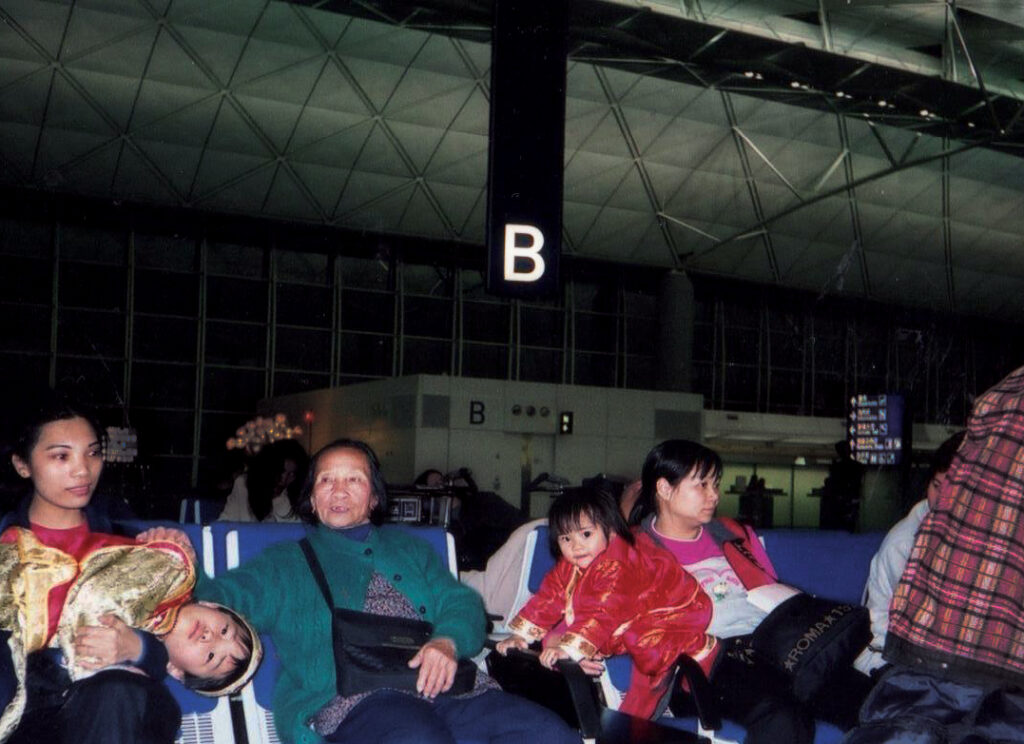 A multi generational family sits in a waiting area of an airport with their luggage.