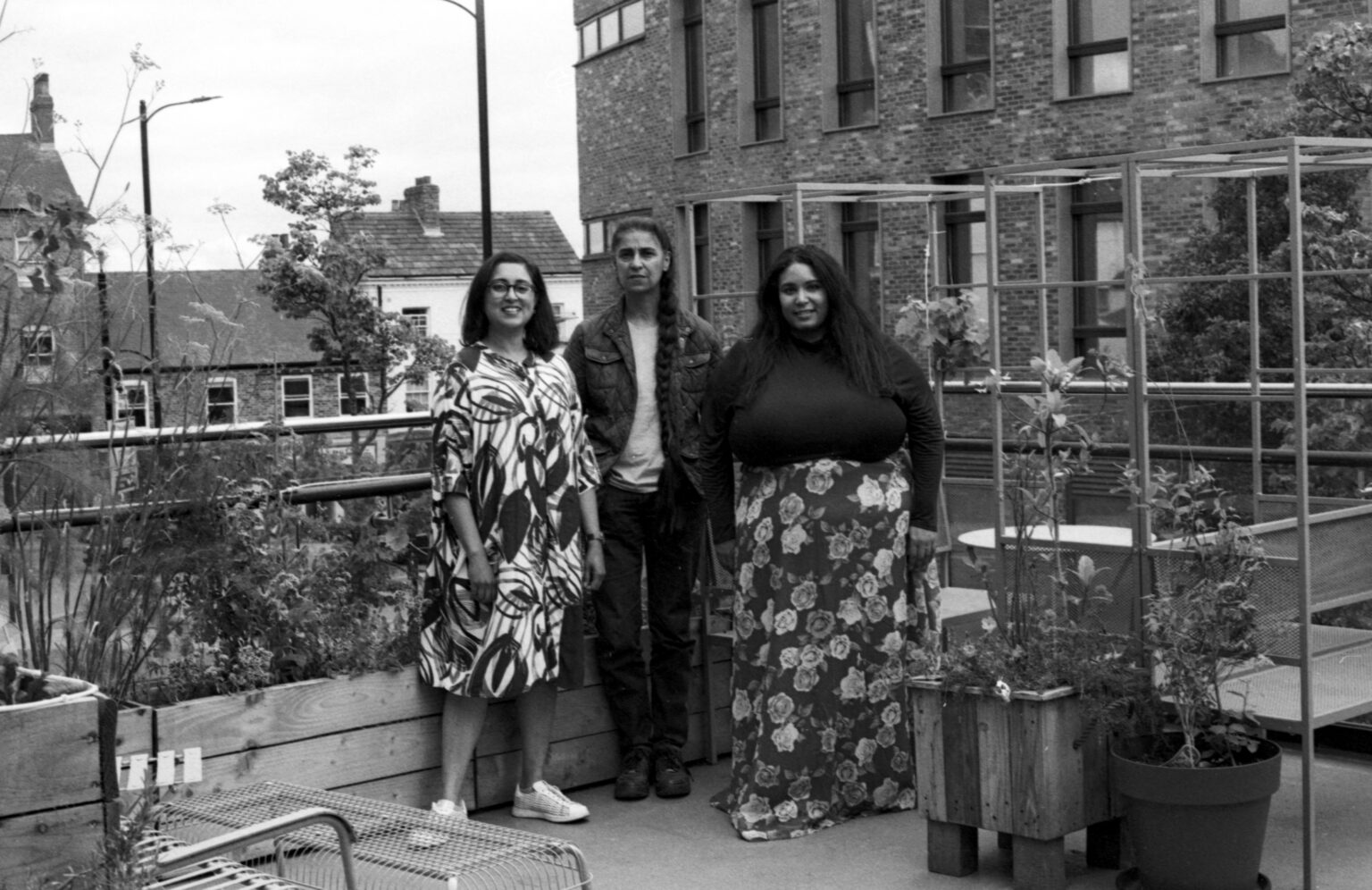 A black and white photo of three women standing together on an outdoor terrace.