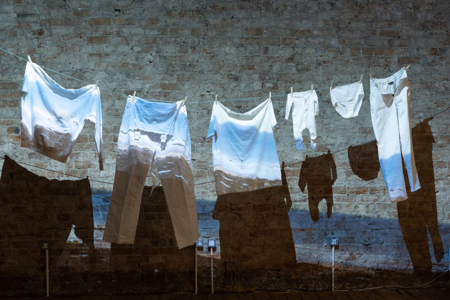 A washing line with white clothing hanging, in front of a brick wall
