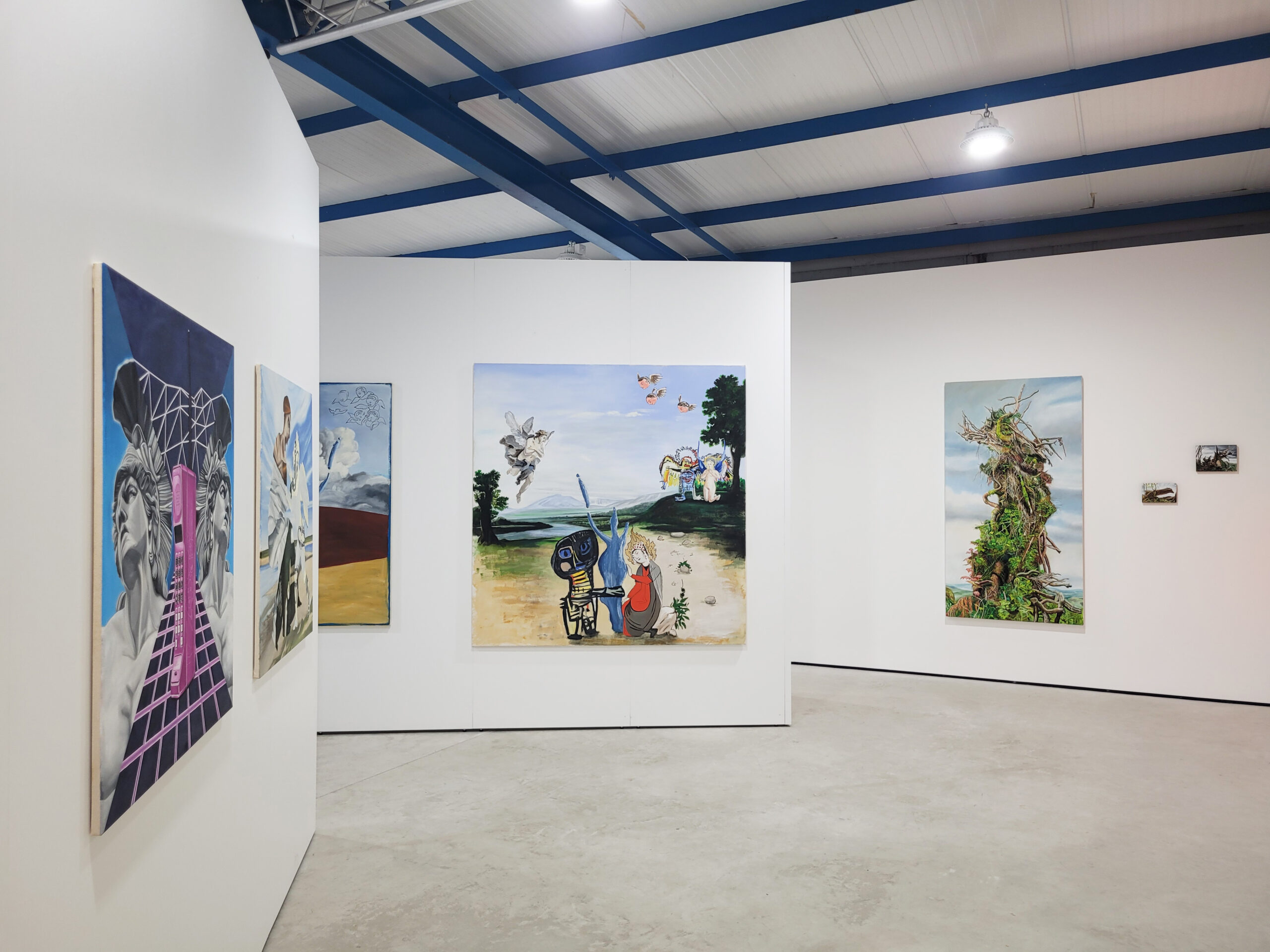 Installation view with multiple paintings visible including a scene on a beach and an overgrown tree trunk