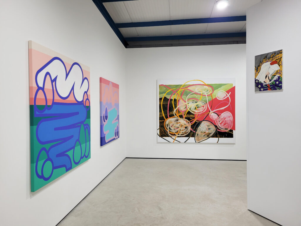 Installation shot of the exhibition with two graffiti like square canvases on the left hand wall and an abstract work straight ahead with pinks greens and browns. A smaller painting is visible in the top right
