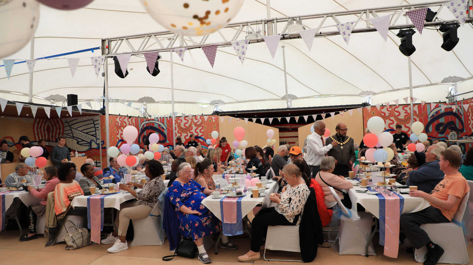 Five long tables laid with afternoon tea with balloons and bunting, it looks like a real party!