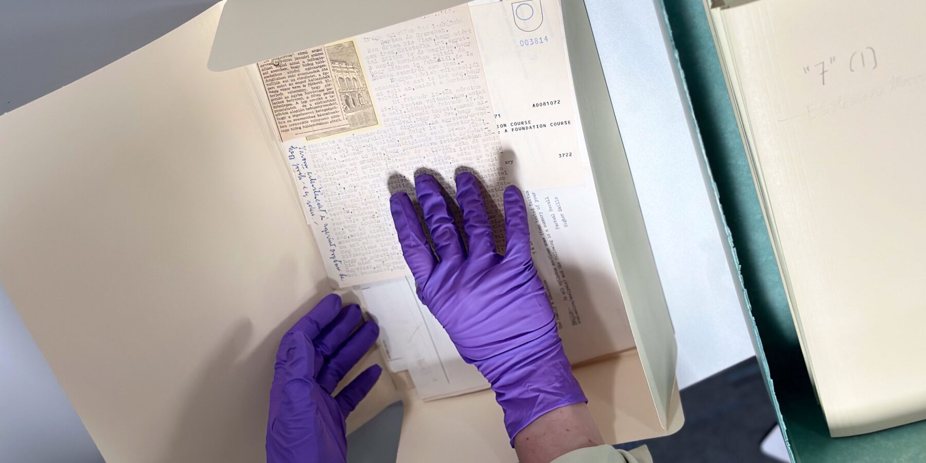 Hands in purple nitrile gloves handle delicate papers