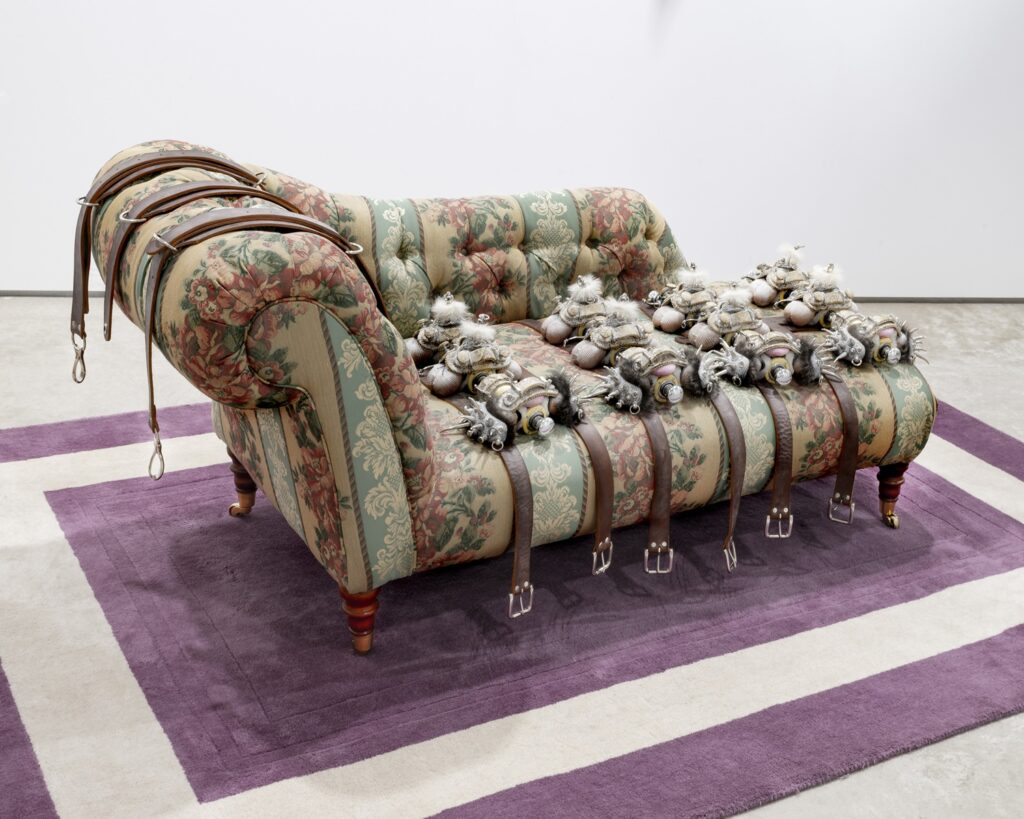 A chintzy chez long with floral fabric covered in metal belts with soft and spiky decorative shapes on them