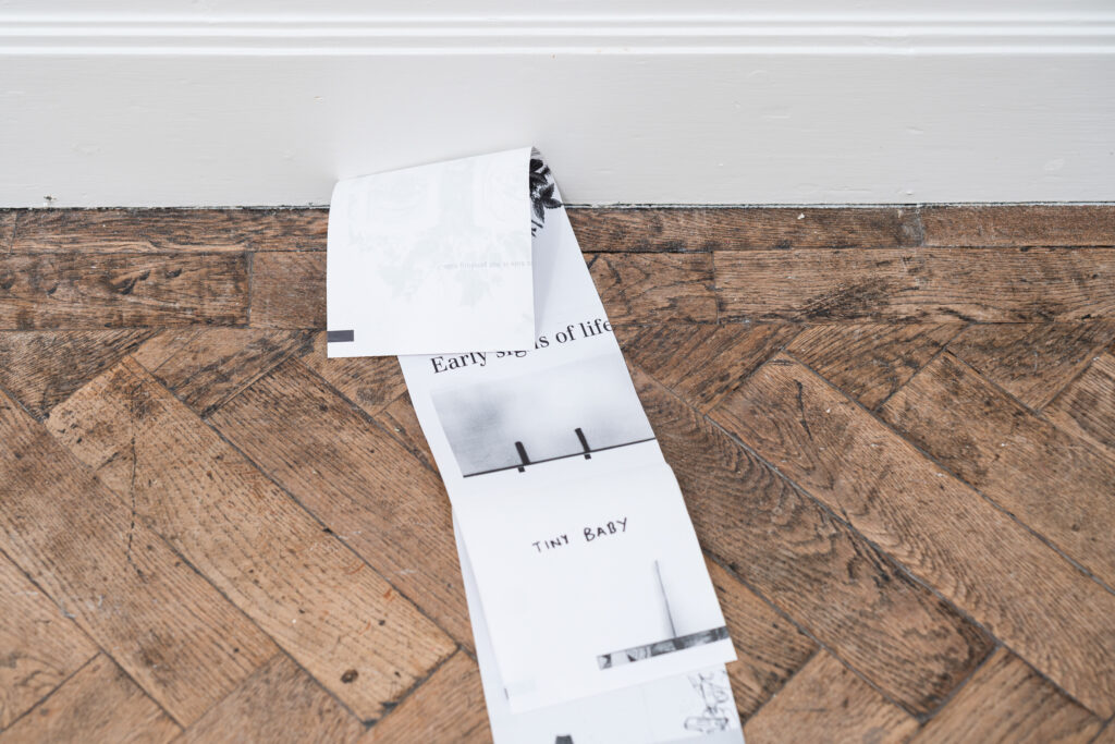 photocopied notes lie on the floor. One note reads 'Tiny Baby'