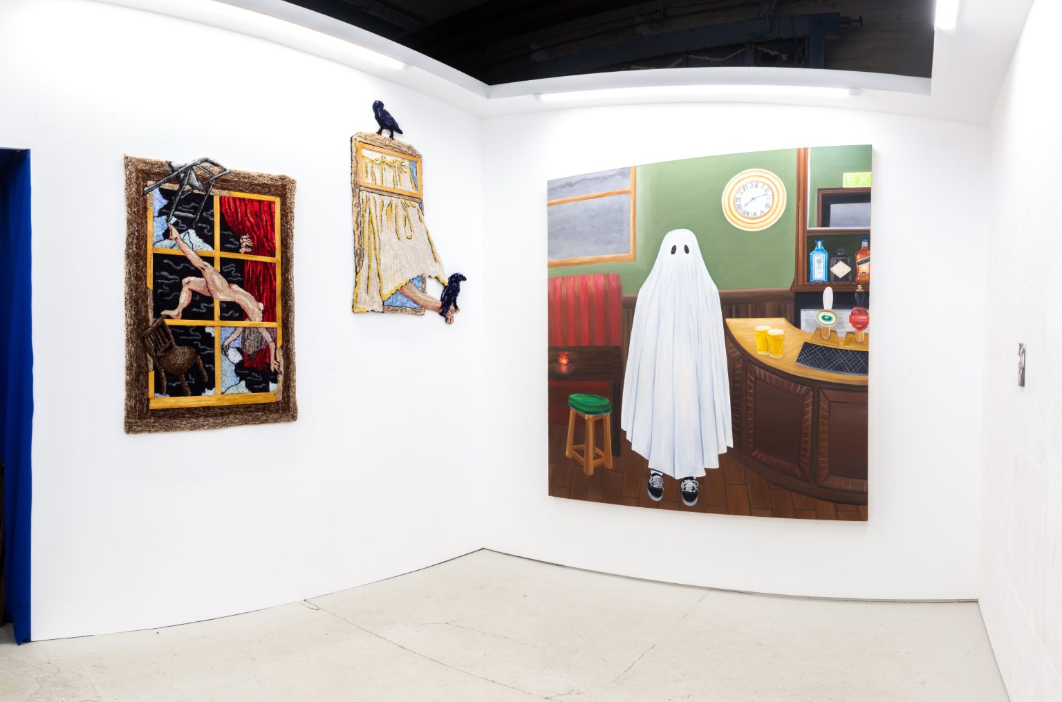 Installation view of the white gallery space with a sliver of the blue entryway visible