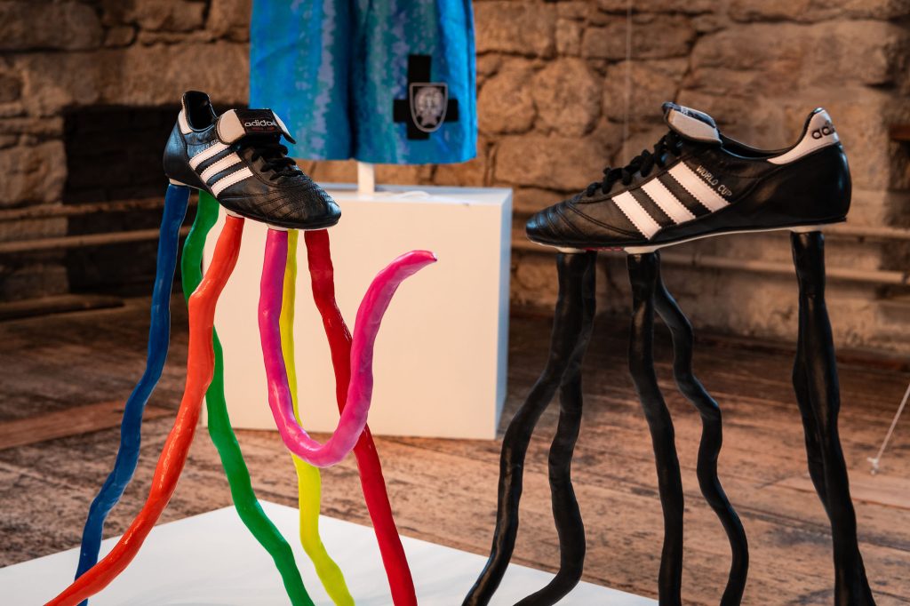 Black and white football trainers are propped up on black and multicoloured tentacles