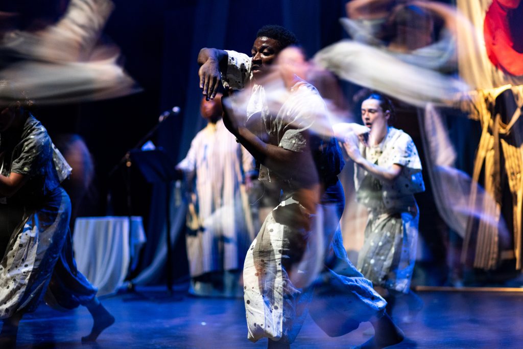 dancers onstage in grey garments make swirling movements
