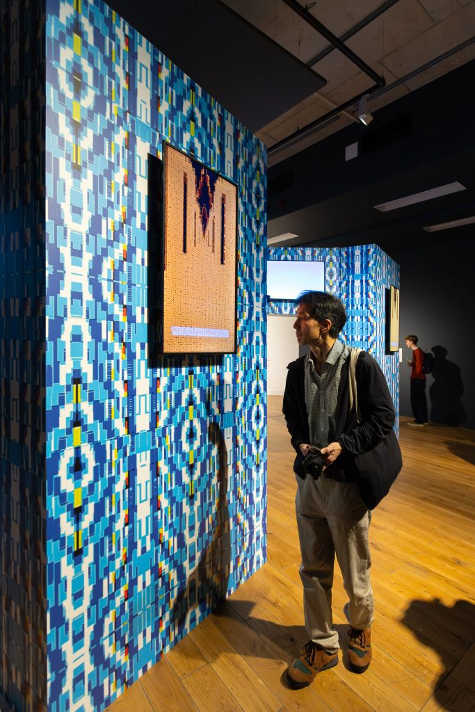 A pixelated blue and white patterned wallpaper with a monitor showing an orange image