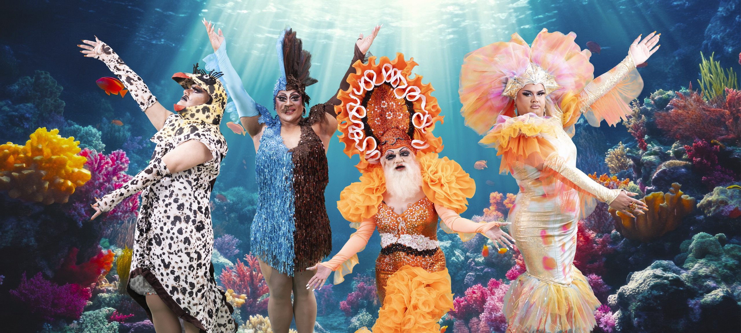 The artist as Darwin in drag with bright orange ruffly skirts, under the sea with three friends dancing