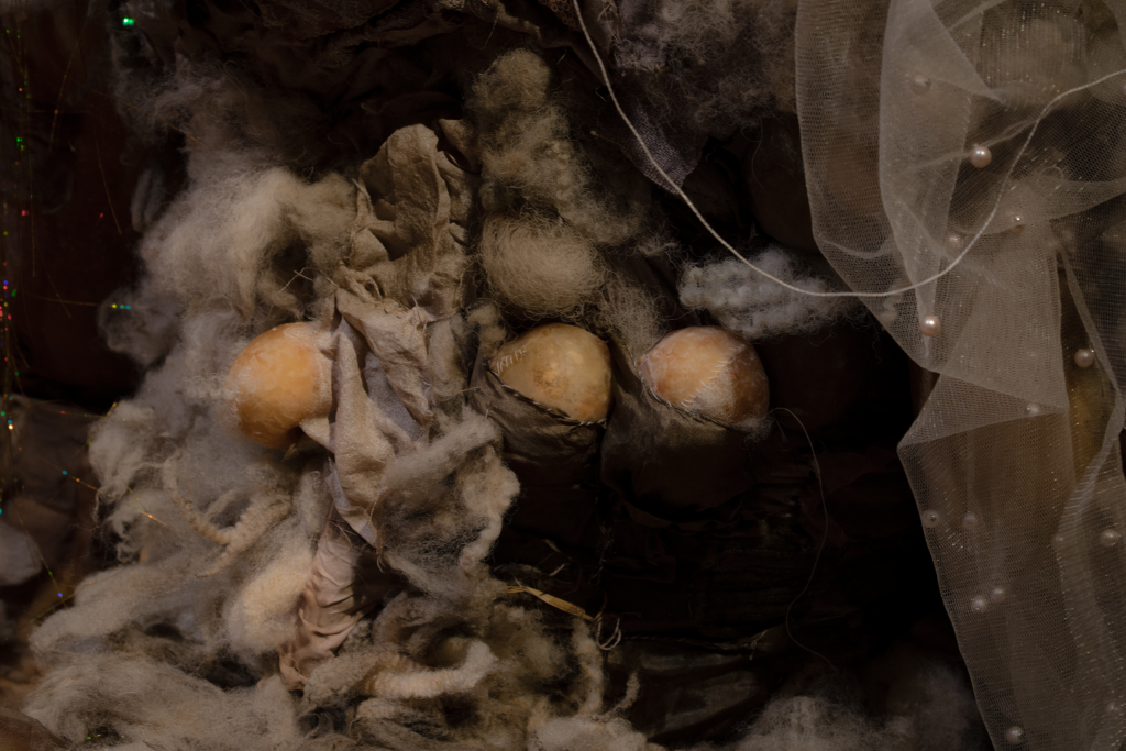 A closeup shot of soft fibrous fabrics in natural earthy tones, studded with pearls