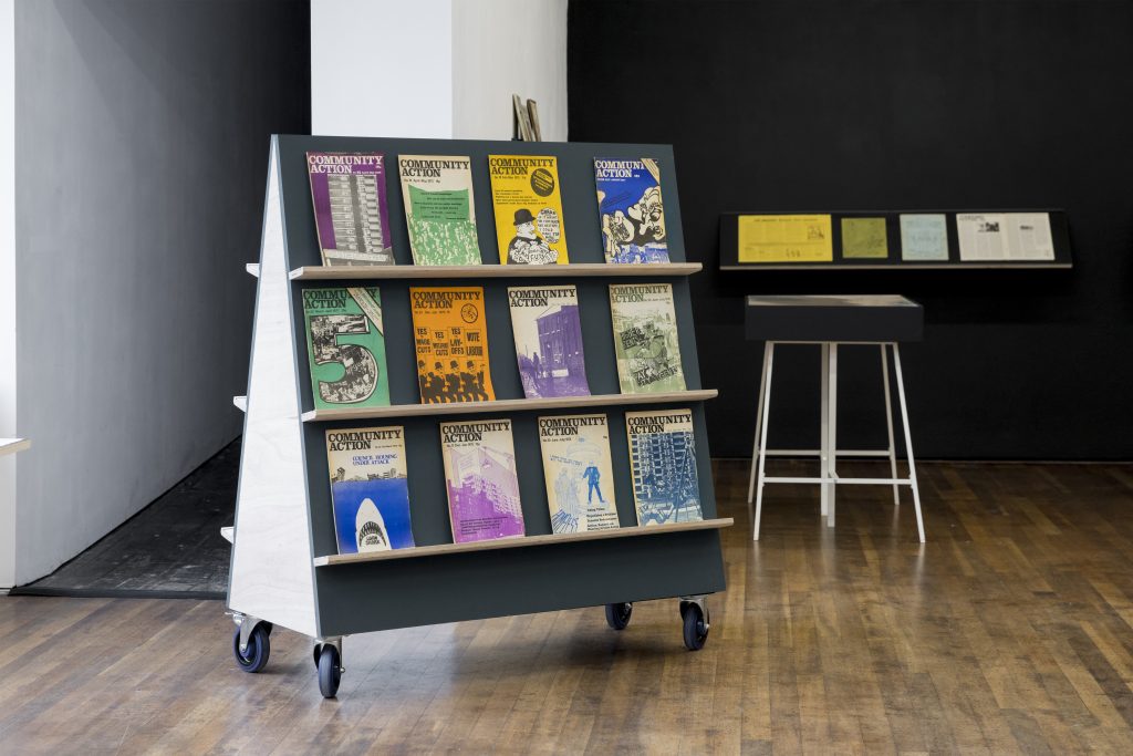 A mini bookcase on wheels with twelve pamphlets showing on it.