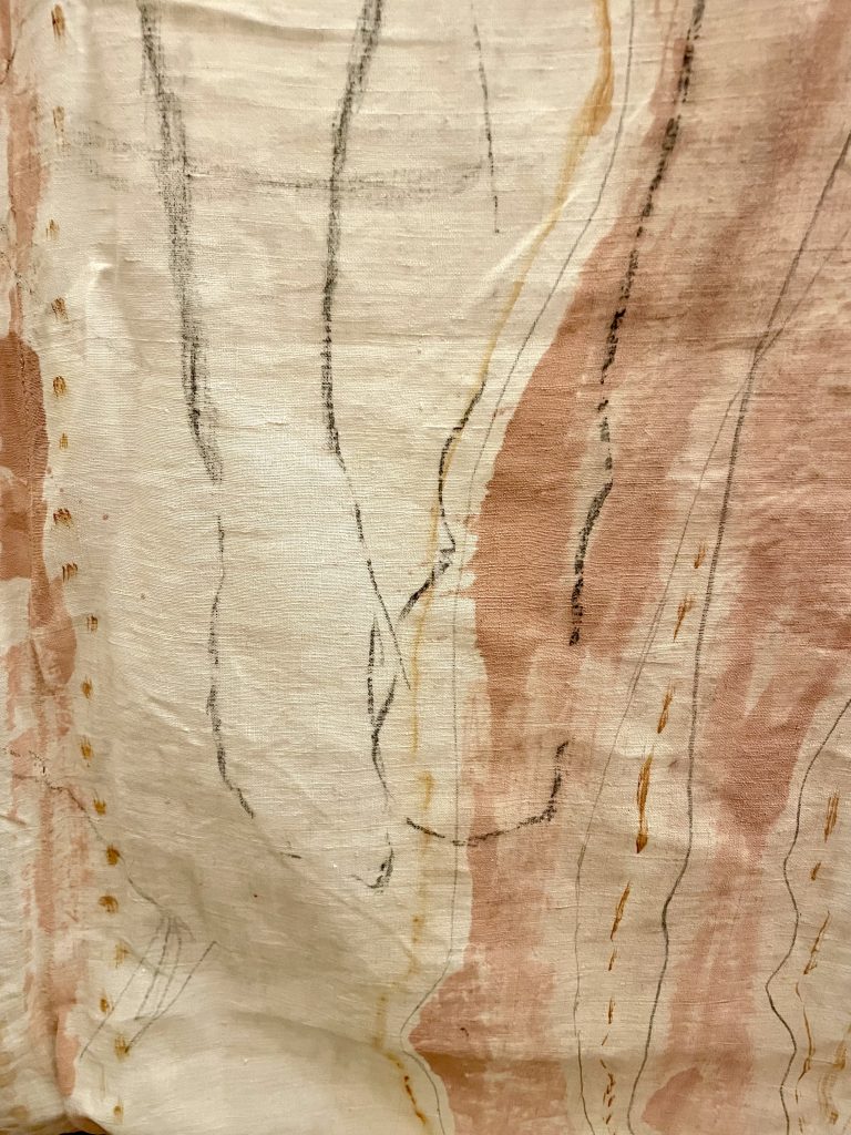a close up of cream coloured fabric with terracotta paint and black lines