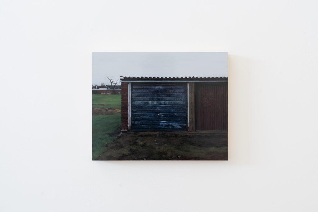 A painting of row of garages under a grey sky, fields visible. behind