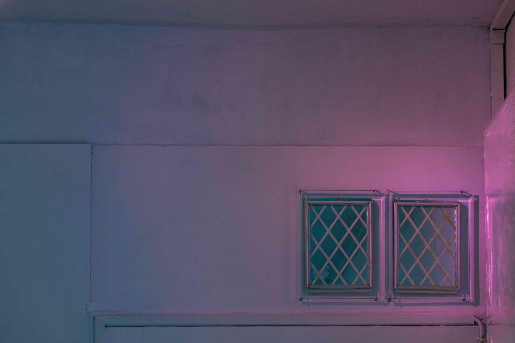 Two framed artworks with a diamond pattern like window leading in a pink light