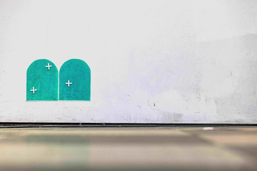 Two small arches painted low on a wall in teal green, decorated with small white crosses