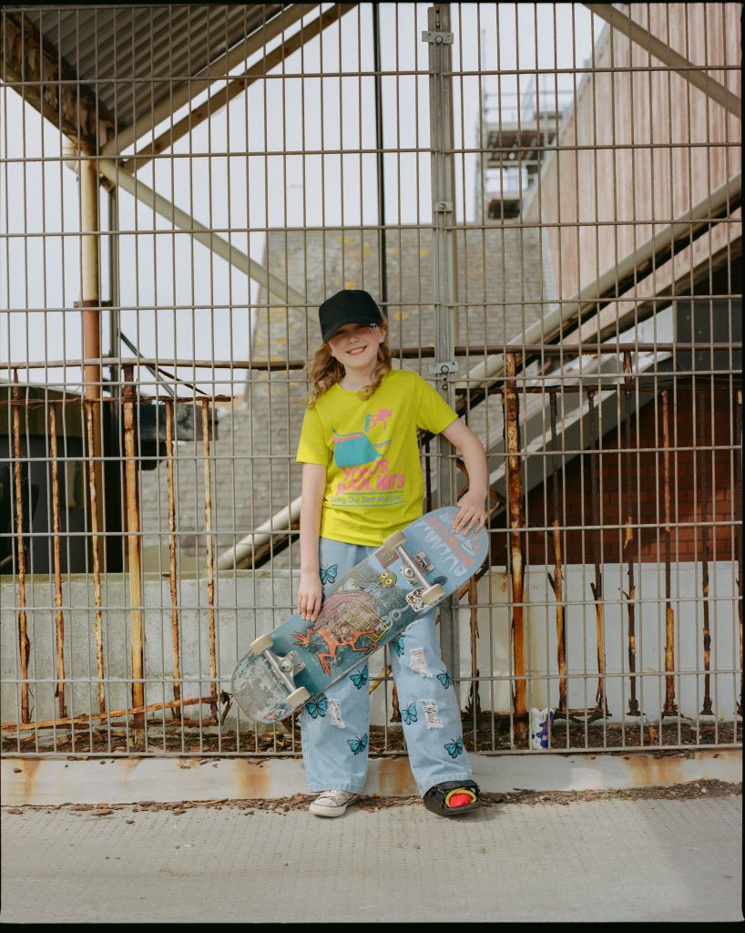A photo of a young white girl smiling and holding a skateboard