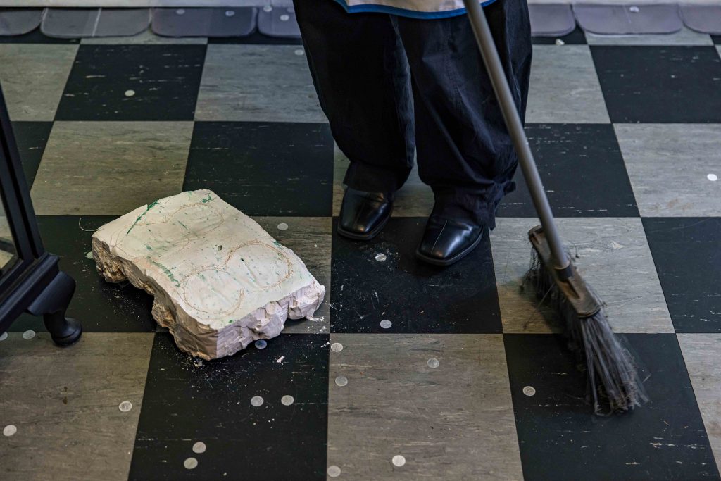 A person's feet. They are dressed as a maid and they sweep the floor