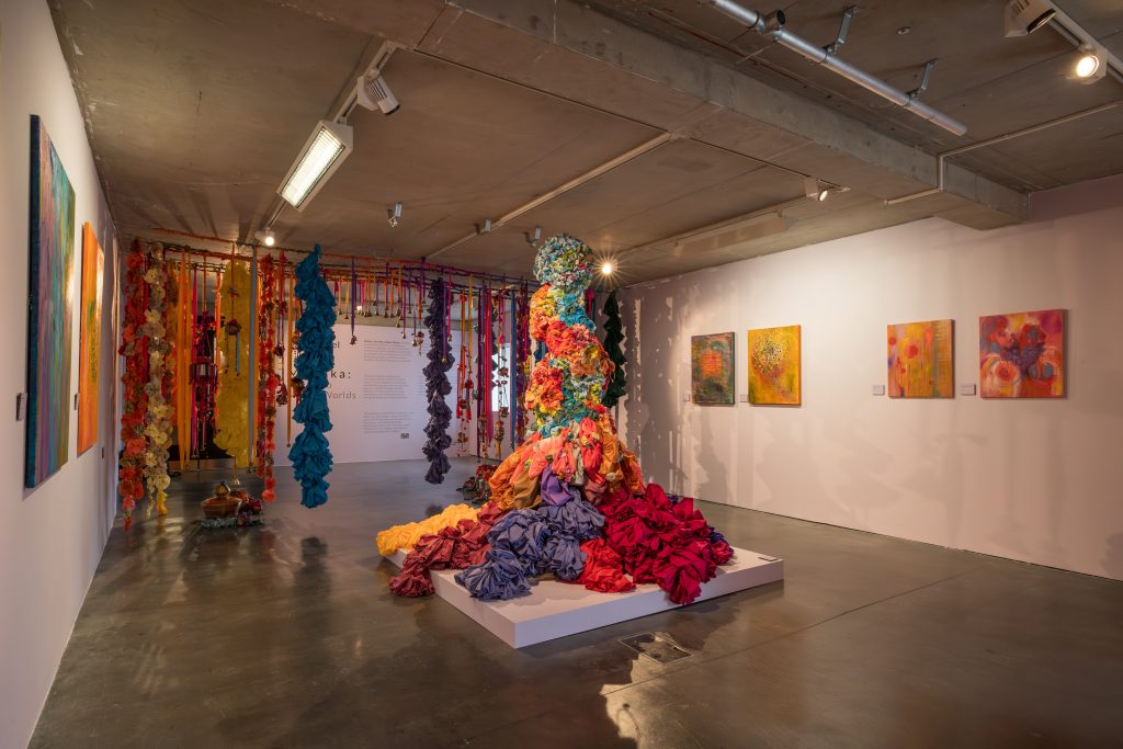 A large fabric sculpture is placed on a low plinth in the centre of the gallery. Fabric spills from the edges of the plinth onto the floor. The sculpture hovers between abstract and figurative - the shape of a figure may be discernable but there are no visible human features.