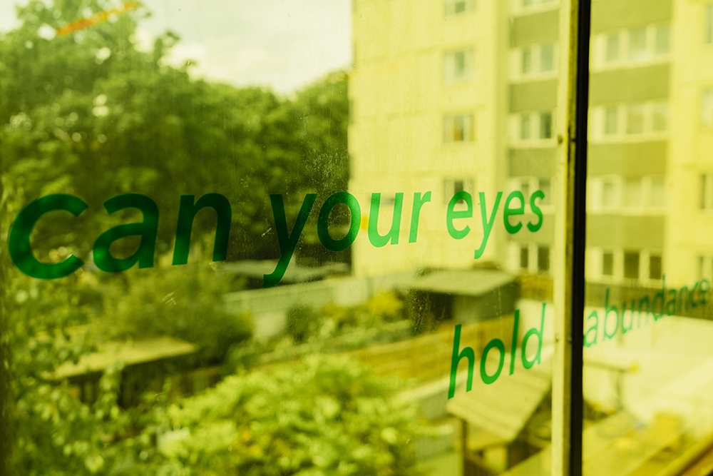 Green vinyl text on a window reads 'can your eyes hold abundance'.