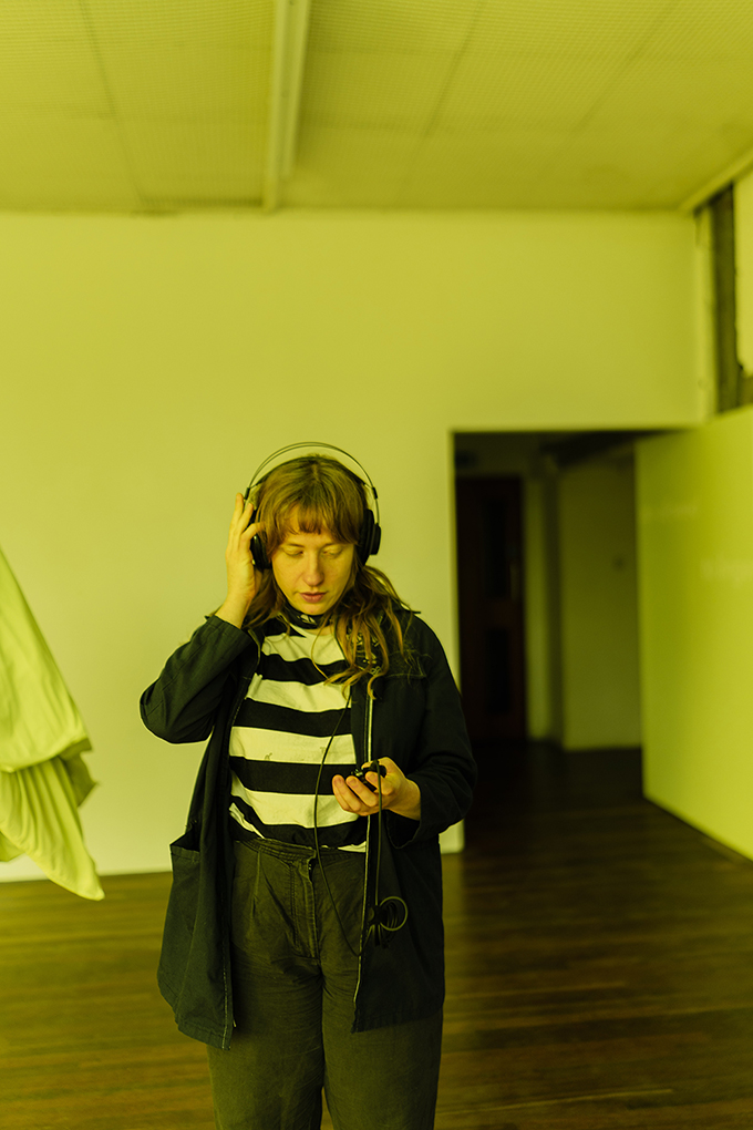 A person in a striped top wearing headphones, listening.