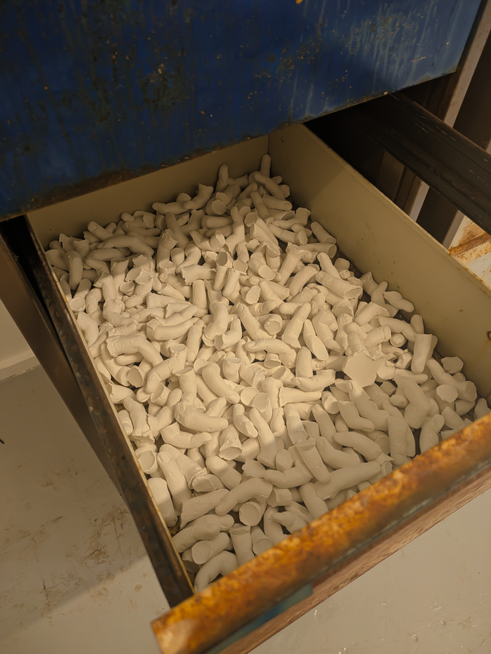 An open cabinet drawer full of hundreds of white plaster casts of human fingers