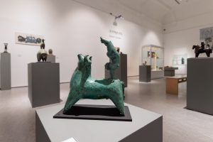 a bronze sculpture of a bull with a man perfoming a handstand on the animal's back