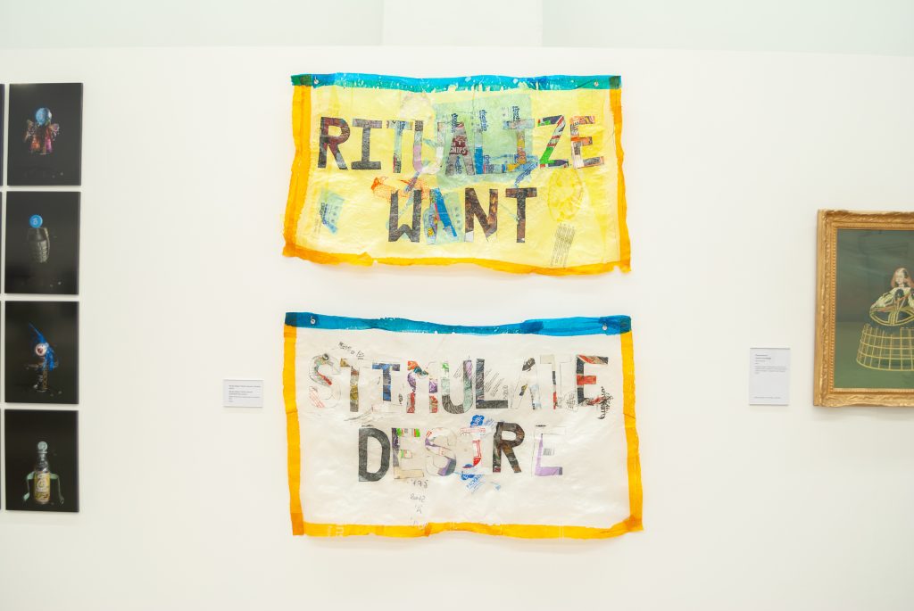 Two multicoloured banners that read RITUALIZE WANT and STIMULATE DESIRE