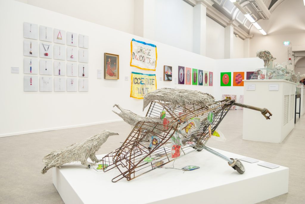 An upturned bent shopping trolley with three paper crows on it