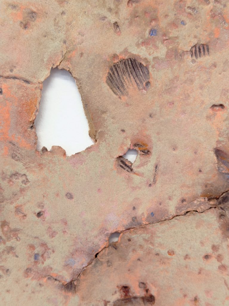 Close detail of a drawing, the paper reddish and torn or imprinted in places