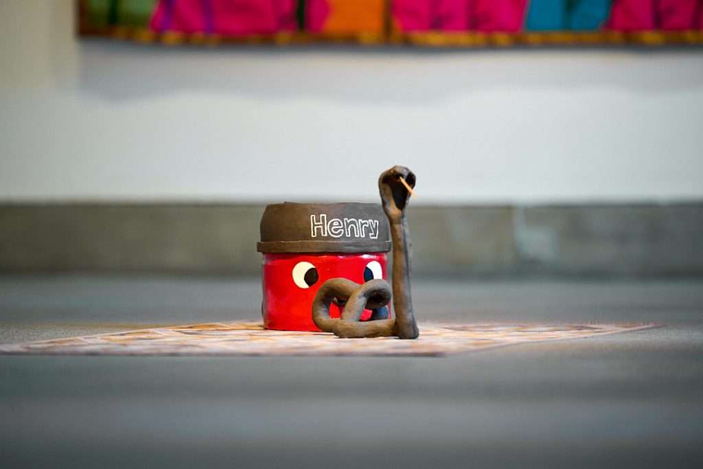 Installation view of a model of a henry hoover. Its vacuum hose has been made to resemble a cobra