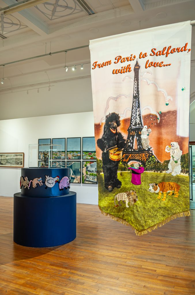 A long banner with the eiffel tower in the iddle and a big black bear playing a marching drum beside it