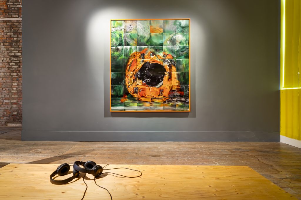 A huge framed abstract image, gridded, of a dark green background, a round orange shape in the middle with a black centre