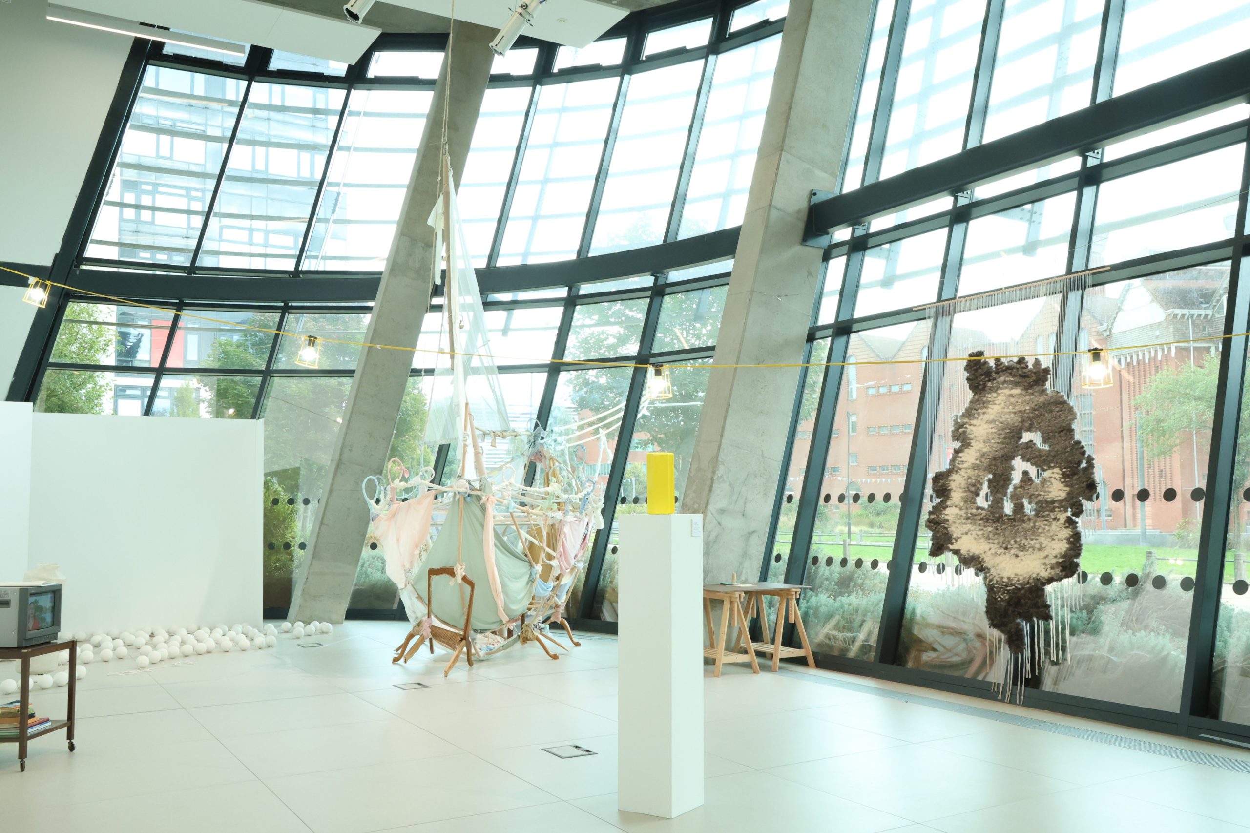 A large glass and concrete room with floor to ceiling windows, a collection of sculptures of different scales and made from different materials are installed around the room.
